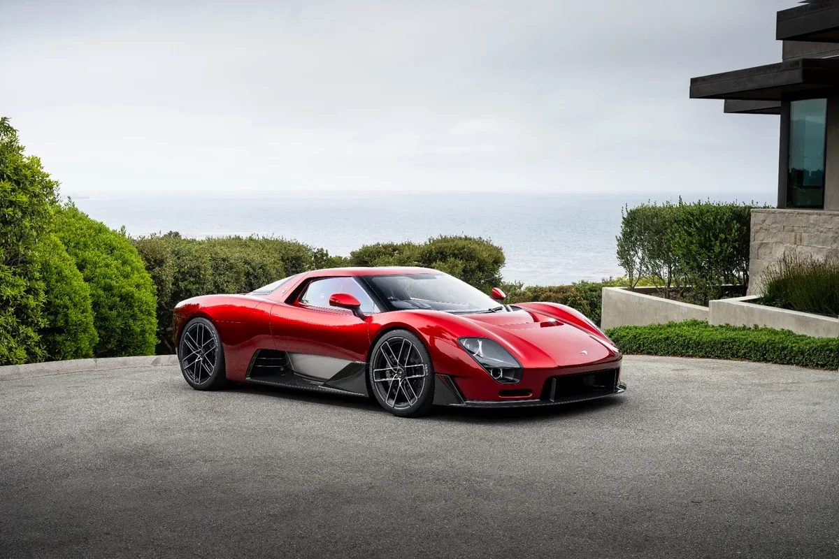 2028 McLaren McL 6GT red supercar front three-quarter coastal view